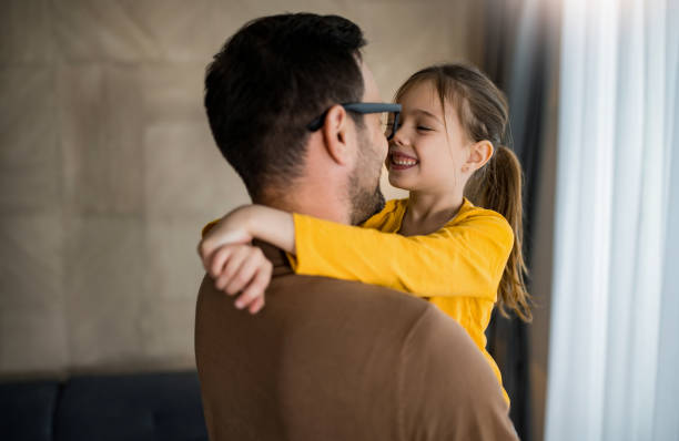 Happy father and his little daughter embracing at home.